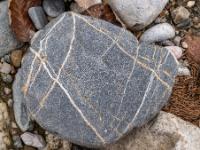 Grauer Stein mit Kreuz und Quermaserung in Weiß und Ocker